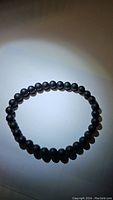 Front view of matt black onyx bead bracelet lying flat on white background, highlighting the matte finish and uniform beads