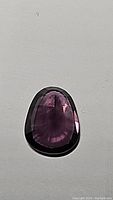 Flat top view of faceted purple gemstone on gray background