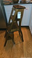 Side view of vintage wood folding chair ladder showing ladder steps and curved legs.