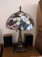 Full view of vintage Dale Tiffany style stained glass table lamp showing butterfly and floral motifs on shade with bronze base and finial.