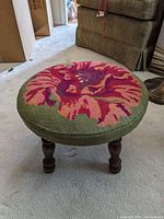 Full view of the vintage stool showing embroidered floral top and wooden legs.