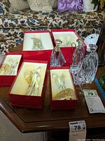 Two angels in red presentation boxes and two standing crystal figures on table.