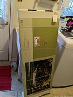 Boxed garden hammock stand with image of product on front, showing steel frame and hammock in outdoor setting.