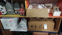 Shelves with various Halloween village houses and boxes containing additional pieces.