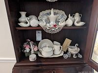Photo of Lenox and Belleek porcelain decorative and kitchen items including swan figurines, vases, candy dish, creamer and sugar, salt shaker and cellar, and small perfume bottles.