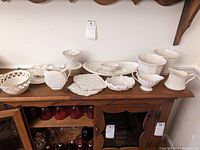 Full display of Lenox white porcelain collection on wooden surface including various candy dishes, pitchers, bowls, gravy boat and small plates.