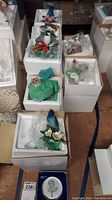 Overview of multiple Lenox bird figurines in original white boxes on a wood floor.