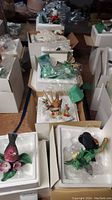 Overview of several Lenox bird figurines with original packaging, shown in a setup on a floor surrounded by packing material and boxes.