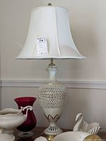 Full view of the Lenox table lamp showing the white fabric shade with braided trim and the ceramic lamp base with pierced lattice design and gilded accents.