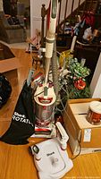 Full view of upright Shark Rotator vacuum featuring dust container, hose, and attached black cloth bag with branding.