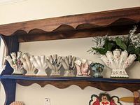 Wide view of all finger vases showing seven 5-finger vases and one three-finger vase with a figurine vase on left end