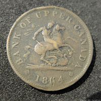 Obverse side of the 1864 Bank of Upper Canada penny token showing Saint George slaying a dragon with text and date.
