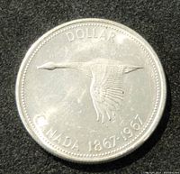 Front side of the coin showing a flying goose in flight with the inscription "DOLLAR CANADA 1867-1967."