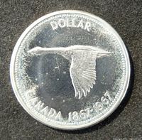 Obverse of Canada silver dollar coin showing flying goose and 'DOLLAR CANADA 1867-1967' inscription.