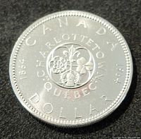 Close-up image of the reverse side of the coin showing the floral design with text 'CHARLOTTETOWN QUEBEC CANADA 1964 DOLLAR'.