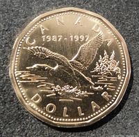 Obverse side of the coin showing the flying loon design with dates '1987-1997' and inscriptions 'CANADA DOLLAR'.