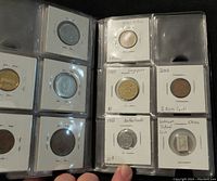 Opened coin collection book showing various international coins including Great Britain, Singapore, Netherlands, and China