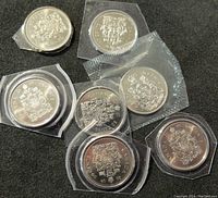 Lot of 10 Canadian 50 cent coins mostly silver with one gold-tone coin. All coins are uncirculated and in protective holders or sealed packaging with dates mostly from late 1980s.