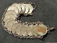 Bracelet laid flat showing coins side by side with visible dates and profile images.