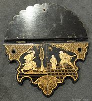 Top view of the black and gilt wall shelf showing intricate Japanese style artwork with three figures and decorative patterns.