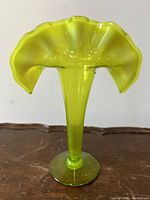 Front view of green hued Victorian style Jack-In-Pulpit glass vase showing flared and ruffled top with elongated stem and round base.