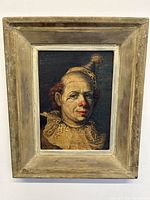 Frontal shot of framed oil painting on board depicting a clown wearing a hat and lace collar, crackle finish visible on paint surface