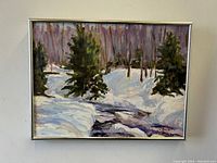 Front view of snow-covered forest stream painting in silver metal frame