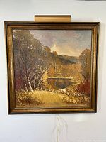 Full view of framed painting on wall showing autumn pond landscape