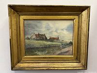 Front view of framed watercolour painting signed Helen C Marshall showing a rural scene with houses and cloudy sky.