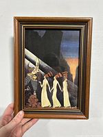 Front view of the framed print held by hand showing the image and condition of the frame.