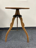 Full view of the three-legged occasional table showing round wooden top and curved legs.