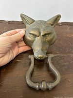 Close-up photo holding the bronze fox head door knocker showing front detail and scale.