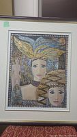 Full view of the framed mixed media artwork showing two female figures with ornate golden headdresses and a nude figure in the background.