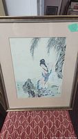 Full framed watercolor painting showing a traditional Japanese woman near water and rocks under willow branches.