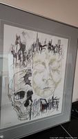 Framed artwork showing the full piece with abstract face, skull, and cityscape elements.