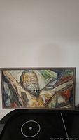 Full view of the framed plaster and tempera artwork depicting an abstract human figure in earthy tones.