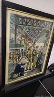 Framed vintage war poster showing military personnel in a train station environment with advertisements on the walls.