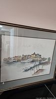 Framed vintage watercolor showing a wide riverside scene with several buildings and a wooden dock in the foreground.