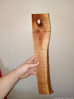 Hand holding the cherry wood serving board showing natural knot and finger hole with live edge profile.