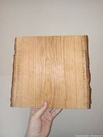 Top view of live edge white oak chopping block held in hand, showing wood grain and natural bark edges