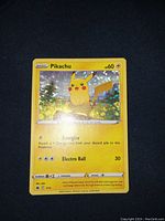 Photo showing a holographic Pikachu Pokemon card with sparkle holo pattern, 60 HP, attacks Energize and Electro Ball, yellow border, approximately 3 inches.