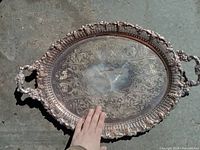 Full view of oval silver plated copper tray with ornate engraved decoration and two handles.