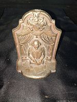 Front view of the cast iron bookend showing William Shakespeare seated under theater curtains with a cherub above.