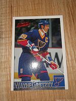 Close up photo of Wayne Gretzky Blues hockey card showing player in blue uniform, on ice with stick ready.