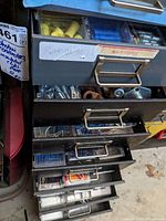 Metal drawers partially open showing assorted electrical connectors and clips sorted in clear plastic bins.
