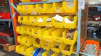 Multiple yellow plastic bins filled with hex cap screws and nuts