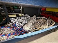 Drawer containing multiple coiled and bundled ropes in different colors and materials.