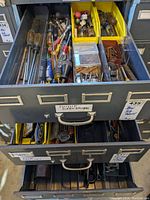 Top drawer with assorted screwdrivers, small tool parts in yellow bins, and other hand tools visible.