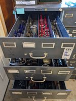 Photo of three open metal drawers showing large quantity of various sockets, socket organizers, and hand tools in organized rows.