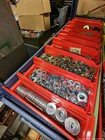 Multiple red plastic bins filled with various steel washers in different sizes, some stacked inside bins.